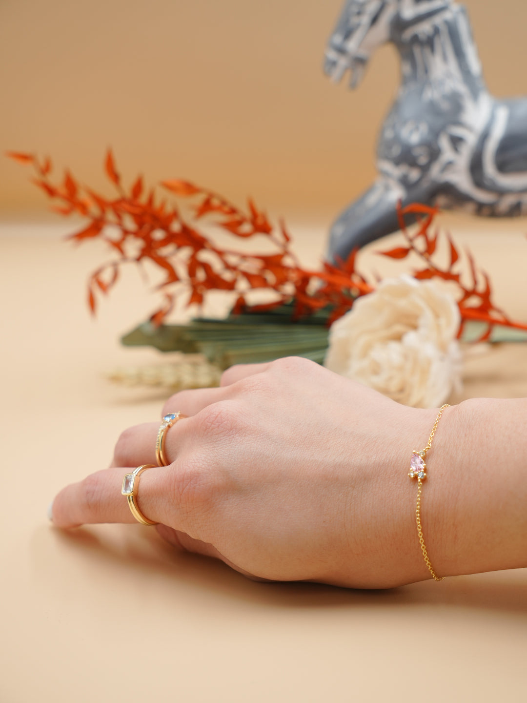 Hand wearing gold rings with decorative background